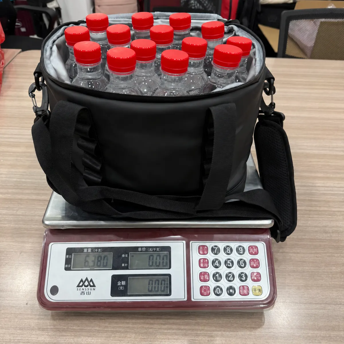 Fourteen red-capped water bottles in the soft cooler on a scale reading 6.380 kg, about 14.1 lb combined