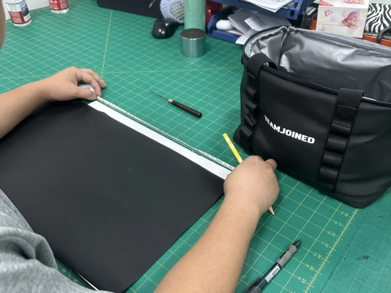 Factory worker measuring a custom cooler bag panel during sample quality review