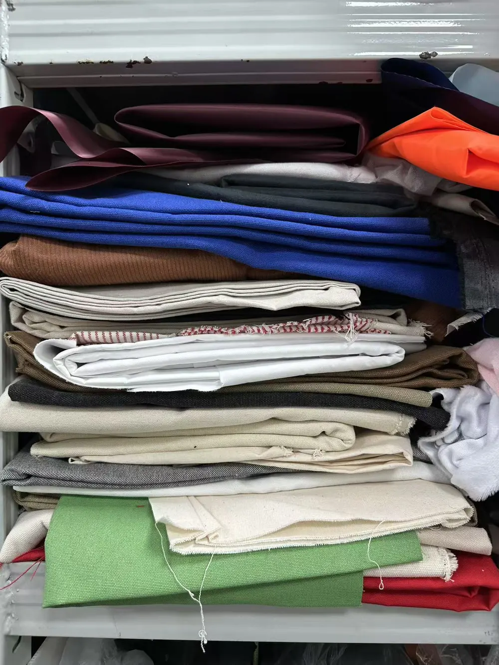 Stacks of differently colored and textured fabrics in Hongzhao's material reference area