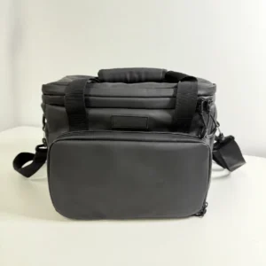 Actual black soft cooler sample with a padded top handle, front zippered pocket and shoulder strap; client logo removed